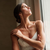 femme portant une robe blanche de mariée ayant a l'oreille une petite boucle d'oreille en marguerite fleurs dorée créateur