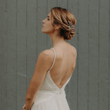 une femme de profil avec un chignon bas tressé,elle porte sur le coté gauche un peigne en porcelaine mate