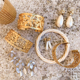 nature morte de différentes manchettes en laiton dorées à l'or fin,d'un bracelet torsadé en résine et laiton doré à l'or fin Aurélie Bidermann et boucles d'oreilles en perles