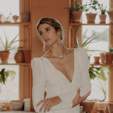 femme de face en robe de mariée avec un grand décoleté en v qui porte un collier en plaqué or et nacres