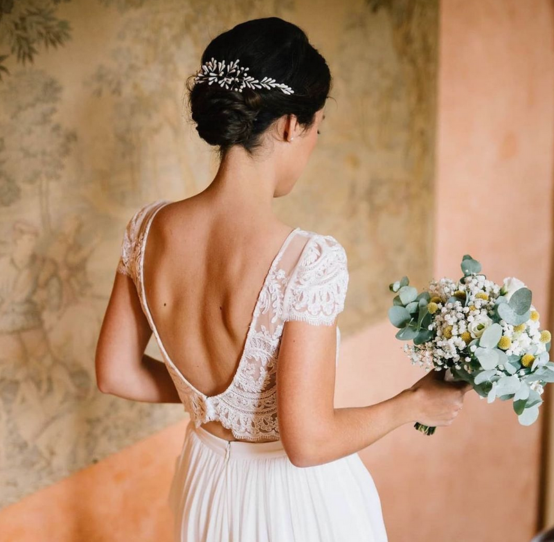 la femme porte une robe de mariée avec un haut. en dentelle ainsi qu'un accessoire couronne de mariage mariée  en porcelaine